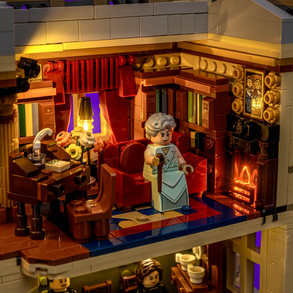 Lampe illuminée près d’une fenêtre aux rideaux ouverts et cheminée de LEGO® Downton Abbey